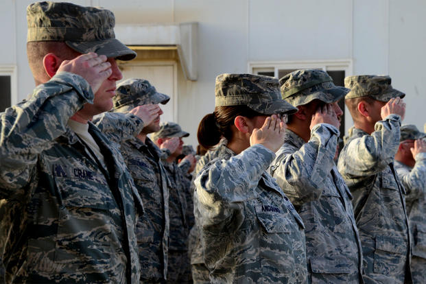 Airmen from the 379th Expeditionary Maintenance Group salute the U.S. flag during a ceremony at Al Udeid Air Base, Qatar. Members of the unit reported sickness caused by mold on the base. (US Air Force photo/Kia Atkins)