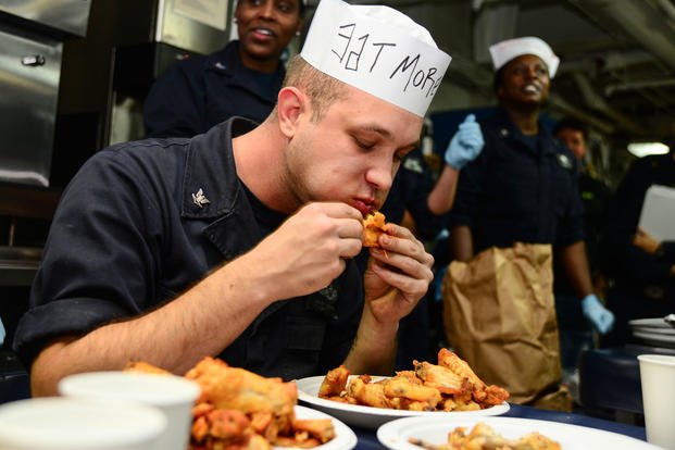 A sailor competes in a wing eating contest.