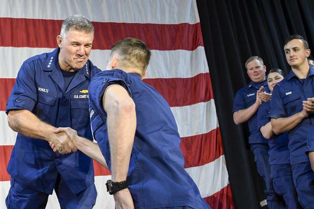 Coast Guard Commandant Adm. Karl Schultz meritoriouly advances Petty Officers 2nd Class Nathan Newberg and Emily Ford.