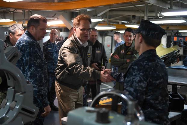 Then Under Secretary of the Navy Thomas B. Modly shakes hands with a sailor aboard USS John C. Stennis.