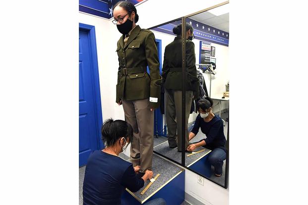 A female soldier has her pants hem measured after receiving the Army Green Service Uniform.