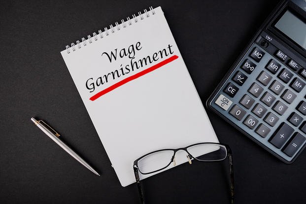 Wage Garnishment word concept written in a notebook with pen and calculator