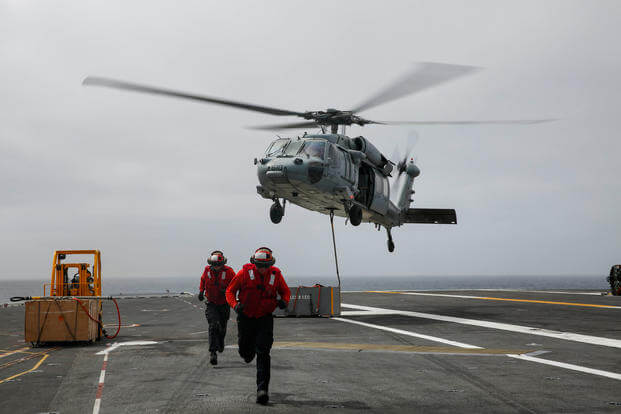 MH-60S Sea Hawk helicopter moves cargo on the flight deck of the aircraft carrier USS Abraham Lincoln