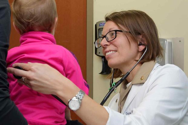 A Navy doctor assigned to family medicine examines a young patient