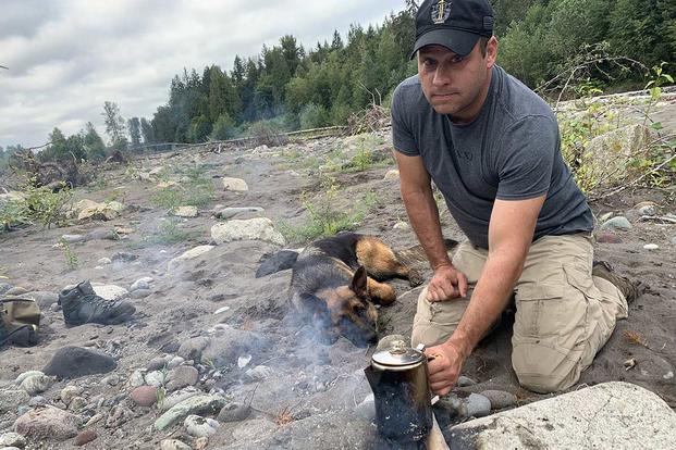 Master Sgt. Earl Plumlee makes coffee from a river with his dog Pepper