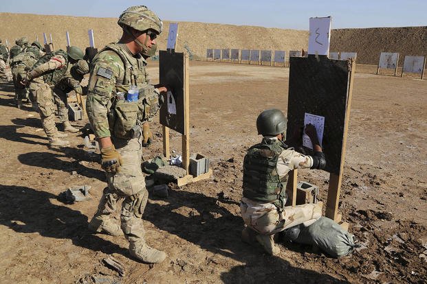 A U.S. soldier watches over an Iraqi security forces member in a shooting drill during a military exercise as U.S. forces train them in Taji, Iraq.