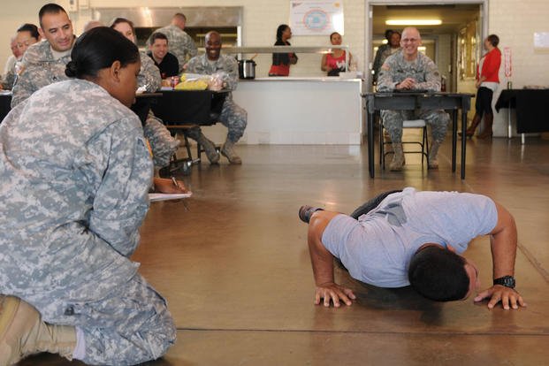 Sgt. 1st. Class Joel Lopez (center) demonstrates push-ups in a mock physical fitness test.