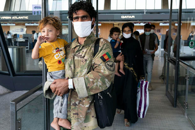 Families evacuated from Afghanistan walk through the terminal at Dulles International Airport.