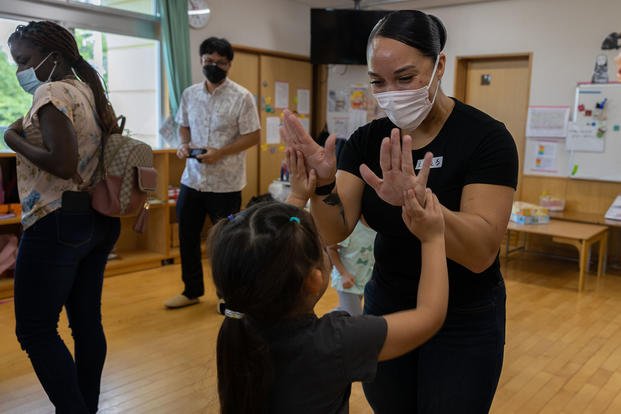 U.S. Marine Corps Sgt. Angelica Clark, a maintenance management specialist assigned to III Marine Expeditionary Force Information Group, celebrates with a student at Suginoko Preschool in Kin, Okinawa, Japan, Sept. 29, 2022.