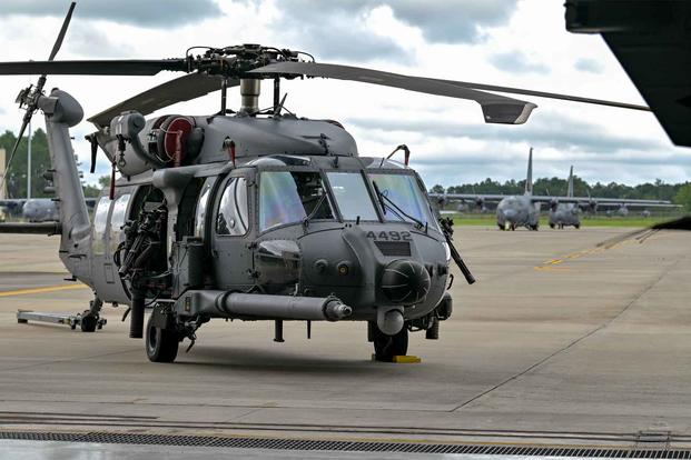 An HH-60W Jolly Green II helicopter is parked.