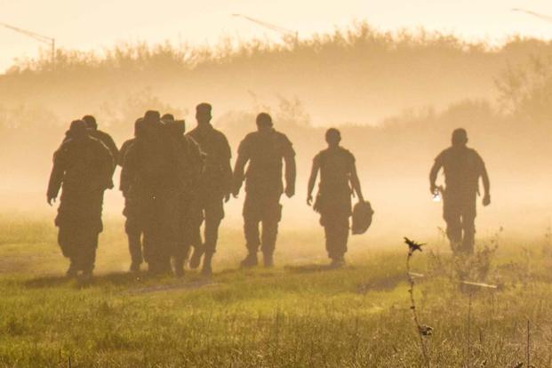 U.S. Army Reserve soldiers walk through a cloud of dust.