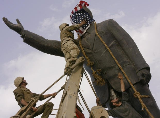 aqi civilians and U.S. troops topple a statue of Saddam Hussein.