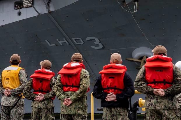 Sailors prepare to moor a ship