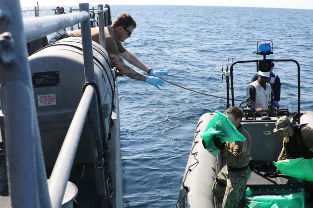 Sailors from patrol coastal ship USS Chinook transfer seized weapons.