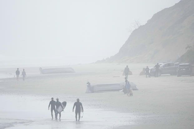 Two boats, one overturned, sit on Blacks Beach, March 12, 2023, in San Diego. 