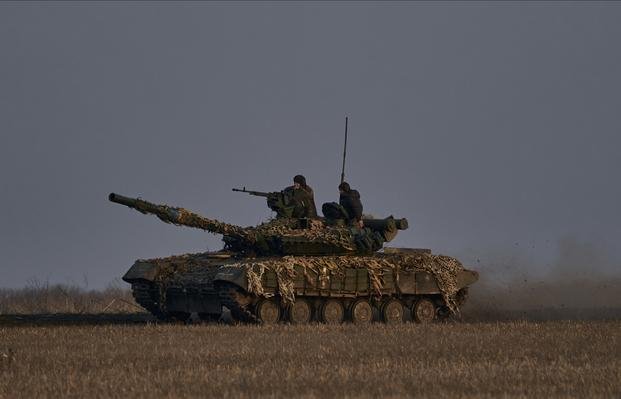 Ukrainian soldiers ride atop a tank on the frontline in Bakhmut.