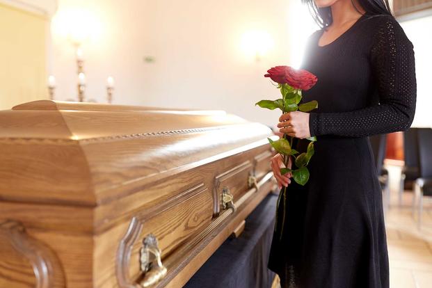 A woman stands next to a casket during a funeral.