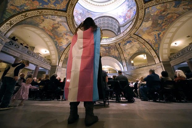 Individual wears a transgender flag at the Missouri Statehouse.