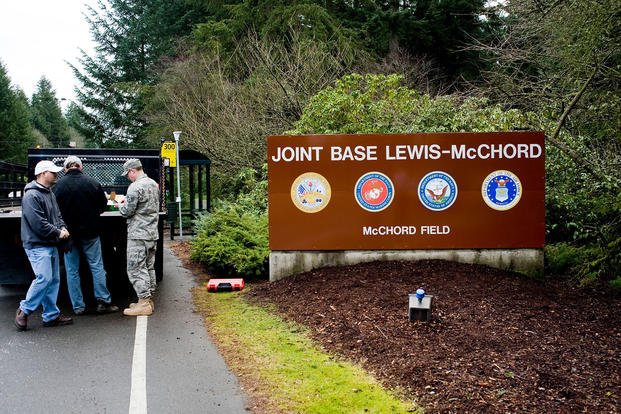 Members of the 62nd Civil Engineer Squadron after installing the new Joint Base Lewis-McChord sign
