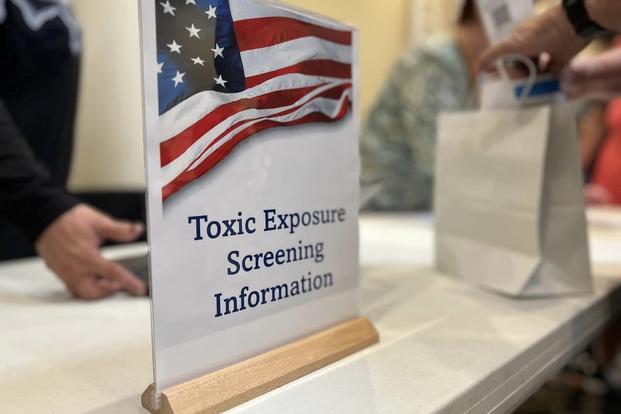 A sign on a table announces states "Toxic Exposure Screening Information"