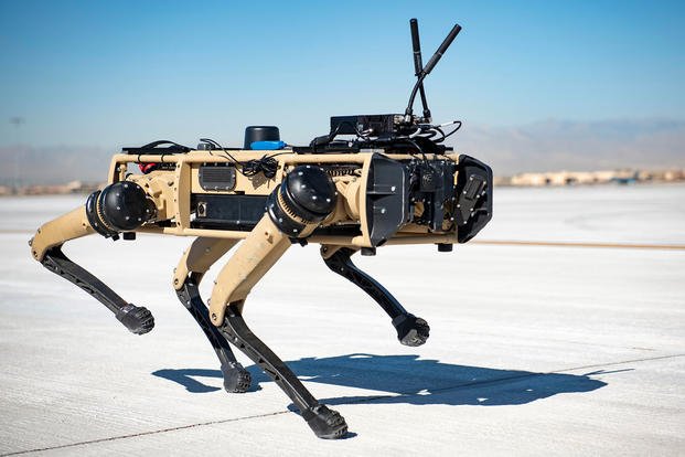 A Ghost Robotics Vision 60 prototype walks with a security forces airman at a simulated austere base
