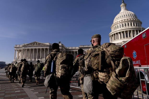 Members of the National Guard walk past the Dome of the Capitol Building on Capitol Hill