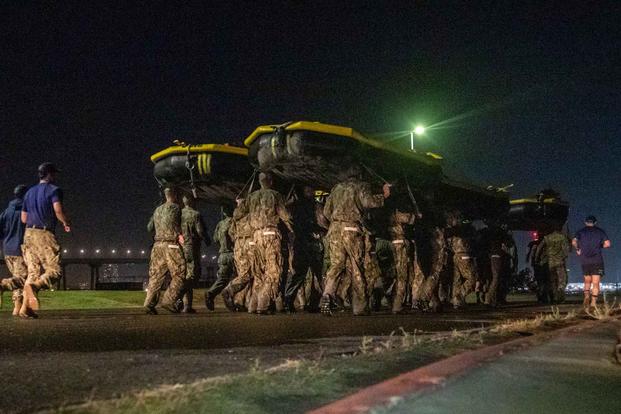 U.S. Navy SEAL candidates run with inflatable boats on their head