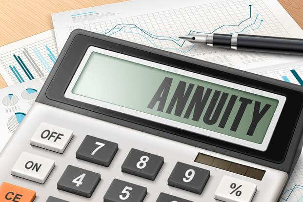 A calculator spells the word annuity on its screen amid other desk items
