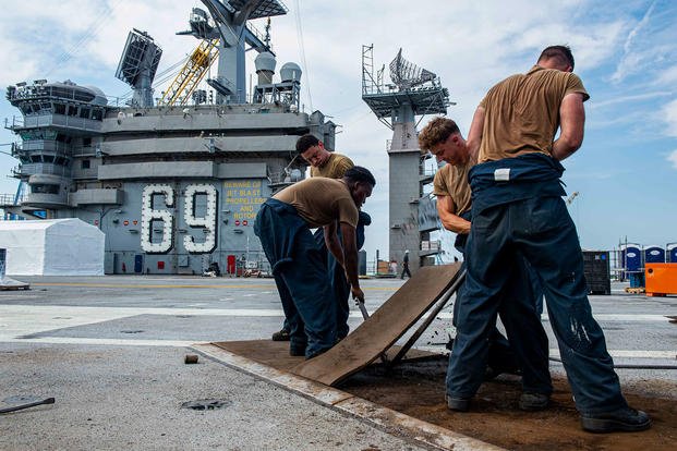 Sailors replace impact pads on the flight deck aboard the Nimitz-class aircraft carrier USS Dwight D. Eisenhower