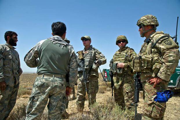 U.S. Air Force Capt. Matthew Zahler and Maj. Jason Helton, air mobility liaison officers, use a translator to talk to Afghanistan border police. (U.S. Air Force/Master Sgt. Jeffrey Allen)