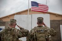 Two soldiers salute the American flag during a ceremony at Camp Taji, Iraq.