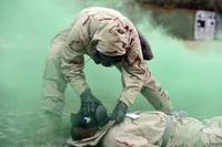 A soldier checks a causality's MOPP mask during a simulated CBRN attack.