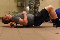 A senior airman uses a foam roller for his back.