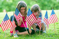Children place flags for Memorial Day while learning the difference between Veterans Day and Memorial Day.
