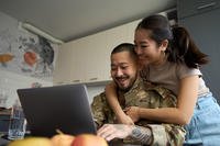 Happy military couple looking at laptop