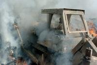 a bulldozer is engulfed in smoke inside a burn pit in Iraq