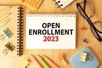 the words open enrollment 2023 are displayed on a spiral notebook