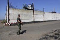 A soldier stands guard next to a wall of a prison in Olenivka