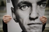 A man holds a poster with a portrait of opposition leader Alexei Navalny