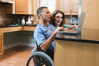 Veteran in wheelchair looking at laptop with wife