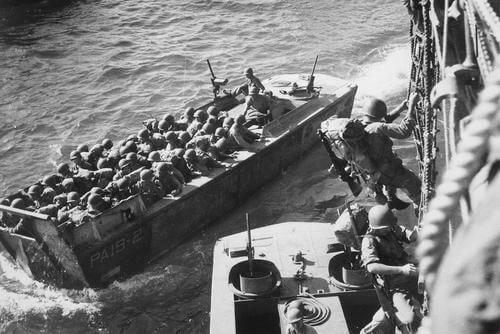 U.S. troops go over the side of a Coast Guard manned combat transport to enter the landing barges at Empress Augusta Bay, Bougainville, as the invasion gets under way.&quot; November 1943. (Photo: National Archives)